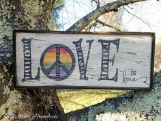 a wooden sign that says love is now painted on the side of a tree trunk