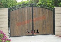 a gated driveway with flowers and trees in the background