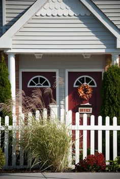 a white picket fence in front of a red door with the words grand illusions written on it