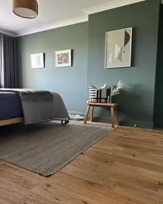 a bed room with a neatly made bed next to a window and a wooden floor