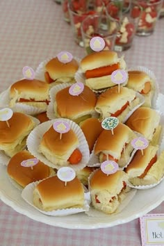 there are many small sandwiches on the plate and cupcakes in paper cups next to each other