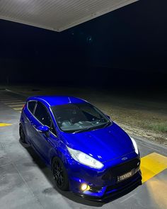 a blue car parked in a parking lot at night