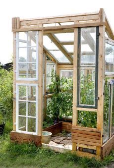 a small wooden greenhouse with plants growing inside