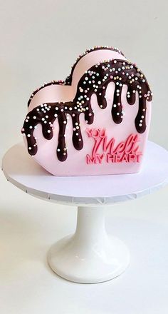 two heart shaped cakes with chocolate icing and sprinkles on top of a white cake stand