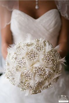 a bridal bouquet with pearls and feathers in the bride's hand at her wedding