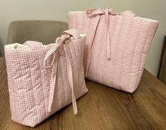 two pink bags sitting on top of a wooden table