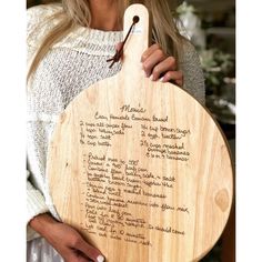 a woman holding a wooden board with writing on it