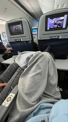 people sitting in seats on an airplane watching tv