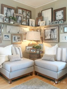 two white chairs sitting next to each other in front of pictures on the wall above them