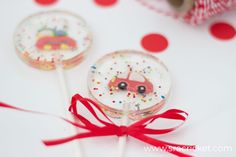 two lollipops decorated with cars and sprinkles