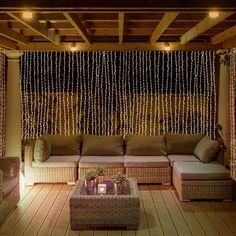 an outdoor living area with wicker furniture and string lights hanging from the ceiling above