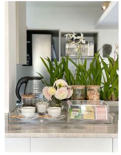 the kitchen counter is covered with flowers and tea cups, along with other items on it