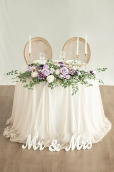 the table is set with two chairs and there are flowers in front of it that says mr and mrs