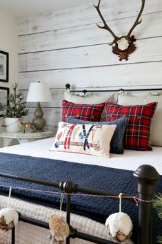 a bed with red and white pillows on top of it next to a wooden headboard