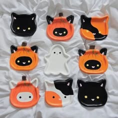 nine halloween plates with black cats and orange pumpkins on white sheeted bedding