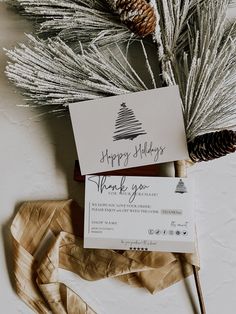 some pine cones are sitting on top of a card that says, happy holidays thank you