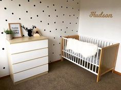 a baby's room with black and white polka dots on the wall, crib and dresser