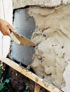 a person is using a pair of scissors to cut through the cement on a wall