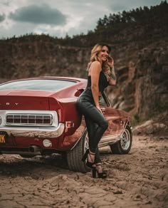 a woman leaning on the hood of a red car