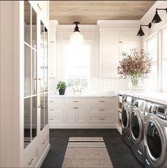 a washer and dryer in a white laundry room with wood ceilinging, windows, and cabinets