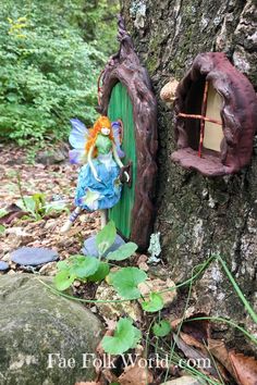 a fairy door in the shape of a tree stump with a doll sitting on it