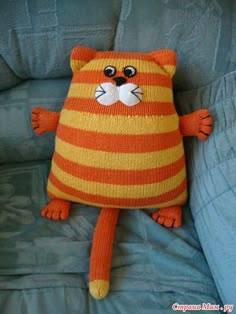 an orange and yellow cat knitted on top of a blue couch with its eyes wide open