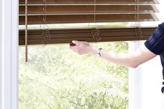 a woman is opening the blinds with her hand