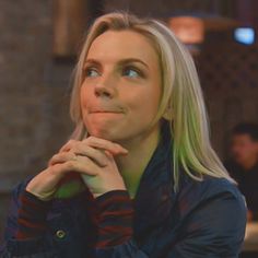 a woman with blonde hair and blue eyes looks up into the sky while sitting at a table