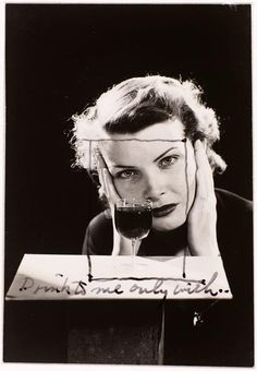 a black and white photo of a woman with a glass of wine in front of her face