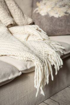 a white blanket sitting on top of a couch next to pillows and throw pillow covers