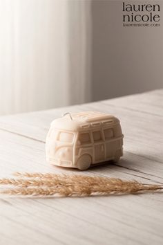 a small toy bus sitting on top of a wooden table next to a wheat stalk