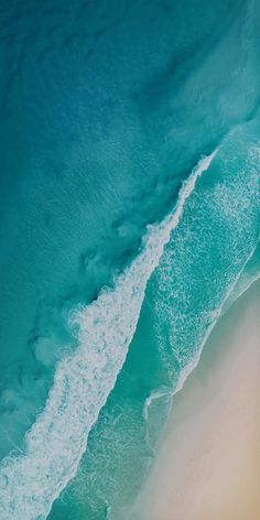 an aerial view of the ocean and beach with waves coming in from the water, taken from above