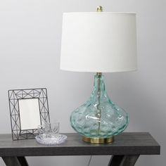 a table with a lamp and a mirror on it next to a framed photo in a frame