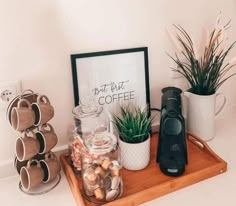 there is a coffee maker on the counter next to some cups and mugs with plants in them