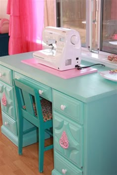 a sewing machine sitting on top of a green table next to a pink chair and window