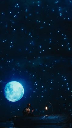 a person sitting on a boat in the water at night under a full moon and stars filled sky