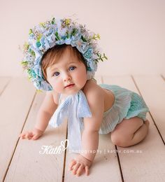 a baby is wearing a blue and white flower headband while crawling on the floor