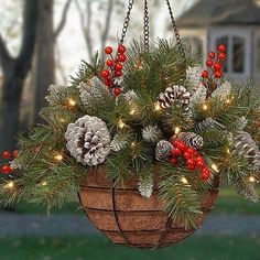 a hanging basket filled with pine cones and red berries is adorned with christmas lights as the decoration