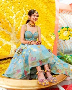 a woman sitting on top of a wooden chair in front of a yellow flower wall