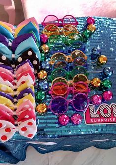 various pairs of colorful sunglasses are on a blue table with sequins and bows