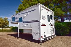 an rv parked in the dirt near some trees