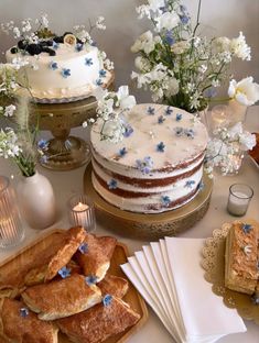 a table topped with cakes and desserts on top of wooden cutting boards next to flowers