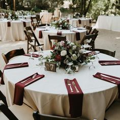 the table is set with white linens and red napkins, silverware, and flowers