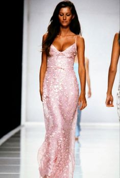 a woman walking down a runway in a pink dress