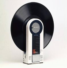 an old fashioned record player with a black disc on it's back side and white background