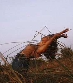 a woman laying on the ground in tall grass