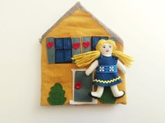 a doll is hanging on the wall next to a yellow house with blue shutters