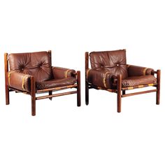 a pair of brown leather chairs sitting next to each other