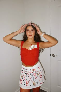 a woman in a red top and white skirt holding her hands up to her head