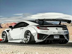 the white sports car is driving down the road in front of mountains and desert landscape